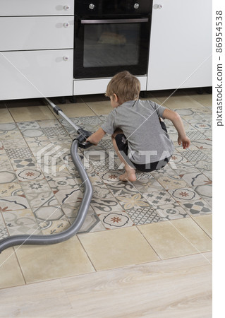 pre-school boy does homework, vacuums floor. Help parents at home. pre-school boy does homework, vacuums floor. Help parents at home. 86954538