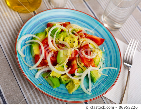 Salad with avocado, tomato and onion at plate 86955220