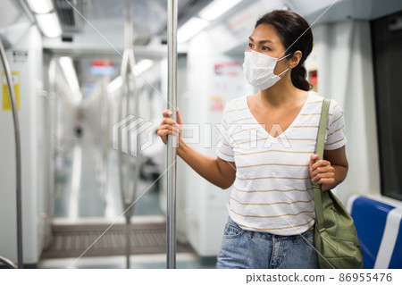 Woman in face mask standing in subway train 86955476
