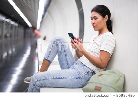 Woman using smartphone while waiting for train in metro station 86955480