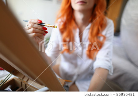 Woman artist sits at home in front of an easel 86956481