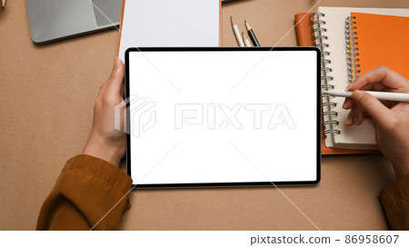 Close-up, Female designer using tablet over minimal office desk. Close-up, Female designer using tablet over minimal office desk. 86958607