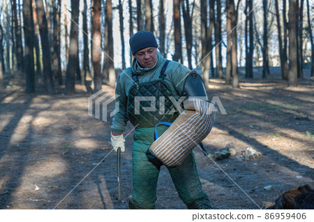 Portrait of a canine instructor training dogs for protective guard duty. A mature man holds a baton and put on a bite sleeve in front of a sheepdog. Training of service dogs Portrait of a canine instructor training dogs for protective guard duty. A mature man holds a baton and put on a bite sleeve in front of a sheepdog. Training of service dogs 86959406