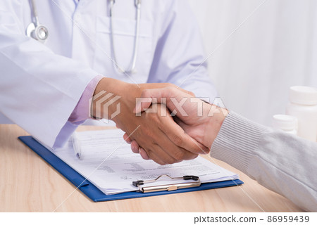 Doctor shakes hands with a patient at the table, closeup 86959439