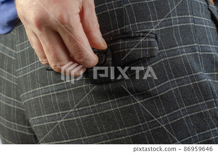 A grown man's hand buttoning the back pocket of his pants. A grown man's hand buttoning the back pocket of his pants. 86959646