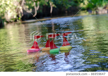 Children's homemade ships floating on a small river or stream. Children's homemade ships floating on a small river or stream. 86959647