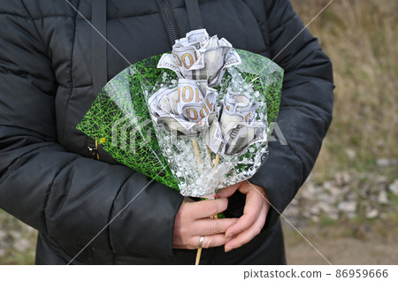 A woman is holding a bouquet of hundred-dollar bills A woman is holding a bouquet of hundred-dollar bills 86959666