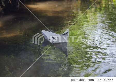 A smoking paper boat floating on a forest river. A smoking paper boat floating on a forest river. 86959667