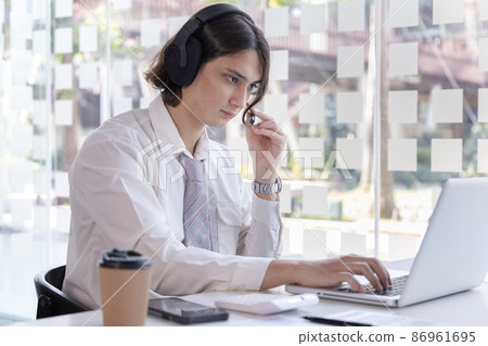 Businessman are greeting friends and manager through video chats and use headphones for communication and business conversations, Online communication, New normal, VDO Call, Internet learning. Businessman are greeting friends and manager through video chats and use headphones for communication and business conversations, Online communication, New normal, VDO Call, Internet learning. 86961695