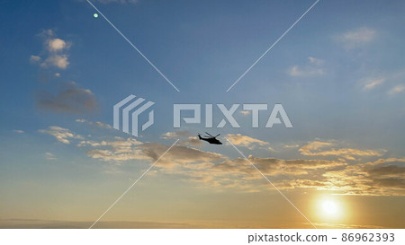 helicopter flies low over a beach in winter at sunset time 86962393