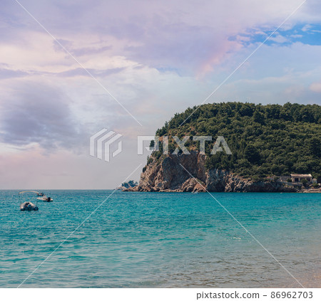 Picturesque view on rocks on a sunny day from the sea. Budva riviera, Montenegro. Aerial view of Sveti Nikola, Budva island, Montenegro. Hawaii beach, umbrellas and bathers and crystal clear waters Picturesque view on rocks on a sunny day from the sea. Budva riviera, Montenegro. Aerial view of Sveti Nikola, Budva island, Montenegro. Hawaii beach, umbrellas and bathers and crystal clear waters 86962703