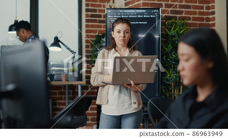 Portrait of caucasian app developer holding laptop looking up and smiling Portrait of caucasian app developer holding laptop looking up and smiling 86963949