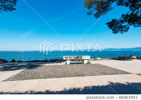 Promenade on the coast of Lake Garda with a Stone Bench - Lazise Veneto Italy 86963991