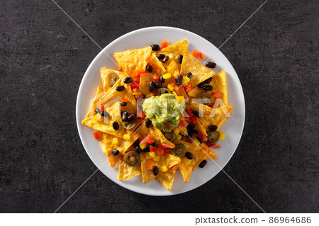 Mexican nachos tortilla chips with black beans, guacamole, tomato and jalapeno 86964686