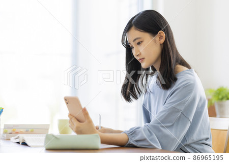Girl studying while looking at a smartphone High school junior high school student Girl studying while looking at a smartphone High school junior high school student 86965195