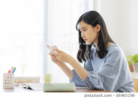 Girl studying while looking at a smartphone High school junior high school student Girl studying while looking at a smartphone High school junior high school student 86965196