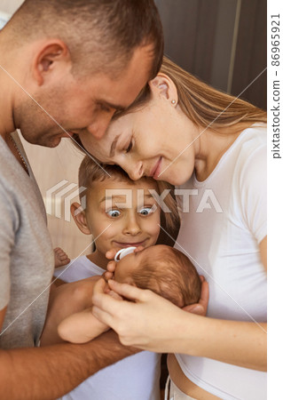 mother, father and daughter are looking at newborn baby 86965921