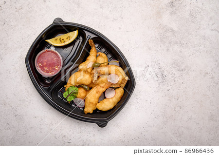 Tempura shrimp with sweet sour chili sauce and radishes in black plastic container Tempura shrimp with sweet sour chili sauce and radishes in black plastic container 86966436