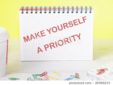 Make Yourself A Priority text on a notebook standing on a table on a yellow background Make Yourself A Priority text on a notebook standing on a table on a yellow background 86966635