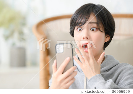 A woman who is surprised to see her smartphone A woman who is surprised to see her smartphone 86966999