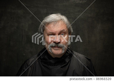 Portrait of cunning senior man looking at camera isolated on dark vintage background. Concept of emotions, fashion, beauty, self-reinvention Portrait of cunning senior man looking at camera isolated on dark vintage background. Concept of emotions, fashion, beauty, self-reinvention 86968320