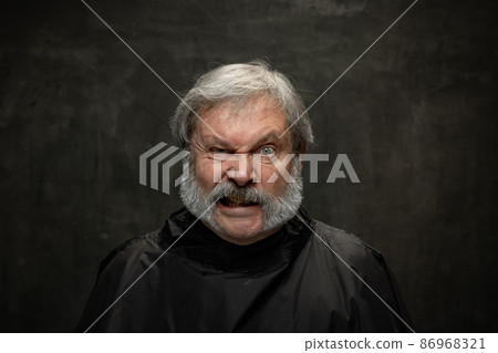 Portrait of angry senior man looking at camera isolated on dark vintage background. Concept of emotions, fashion, beauty, self-reinvention 86968321