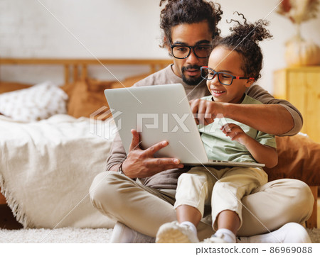 Happy african american family little son with dad watching funny videos on laptop together at home 86969088
