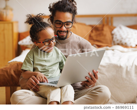 Happy african american family little son with dad watching funny videos on laptop together at home 86969111