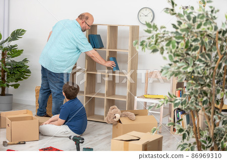 A father and his child stack books together on a bookcase shortly after moving in. A father and his child stack books together on a bookcase shortly after moving in. 86969310