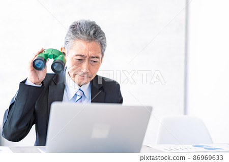 A businessman looking out with binoculars A businessman looking out with binoculars 86969633