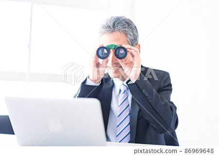 A businessman looking out with binoculars A businessman looking out with binoculars 86969648