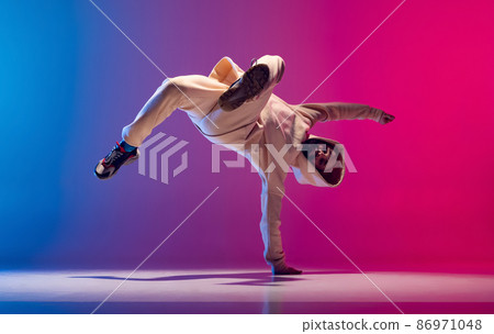 Studio shot of young flexible sportive man dancing breakdance in white outfit on gradient pink blue background. Concept of action, art, beauty, sport, youth 86971048