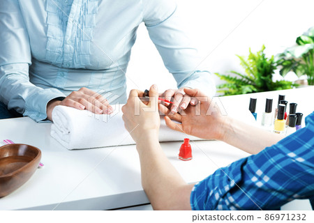 Manicurist working with client's nails at table 86971232
