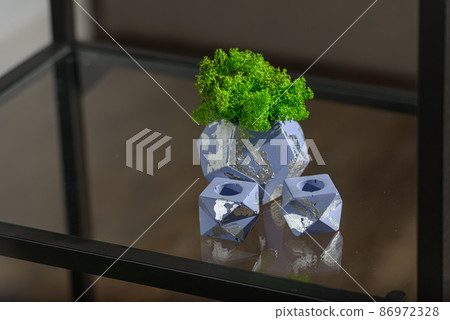 green moss in a violet concrete pot with two candle holders 86972328