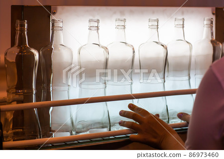 Small liquor production based on maple syrup. Lot of pure alcohol bottles unlabeled. Bottles placed in a row. Person in lab coat analyzing the bottles 86973460