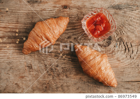 two croissant with strawberry jam on a wooden background, top view. Sweet and hearty breakfast with croissants 86973549