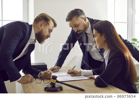 Team of people meeting around table with judicial documents. Experts working with court papers to ensure enforcement of law and justice. Lawyer giving legal advice concerning criminal or civil lawsuit Team of people meeting around table with judicial documents. Experts working with court papers to ensure enforcement of law and justice. Lawyer giving legal advice concerning criminal or civil lawsuit 86973654