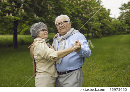 Happy loving mature senior couple dancing in park enjoy weekend time together outdoors. Romantic caucasian grandparent in love having fun relax in forest. Healthcare lifestyle retirement concept 86973660