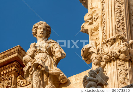 Lecce, Puglia, Italy. August 2021. The church of Santa Croce is the finest example of Lecce baroque. Detail of the facade illuminated by the warm light of the evening. 86973830