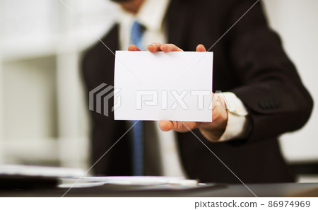 Man's hand showing business card - closeup shot on grey background Man's hand showing business card - closeup shot on grey background 86974969