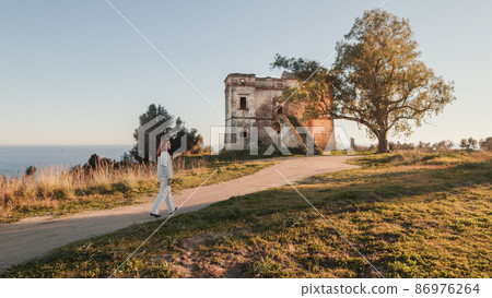 Beautiful girl in white dress enters an ancient castle in the countryside  86976264