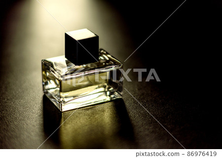 Glass perfume bottle with rosemary sprig on wooden podium Glass perfume bottle with rosemary sprig on wooden podium 86976419