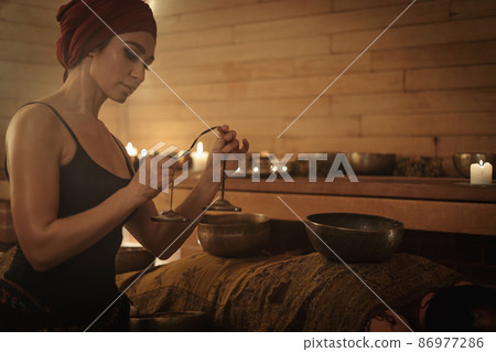 A woman performs a Tibetan ritual with sound bells. The concept of therapy A woman performs a Tibetan ritual with sound bells. The concept of therapy 86977286