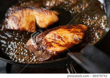 Cook teriyaki yellowtail in a frying pan 86979742
