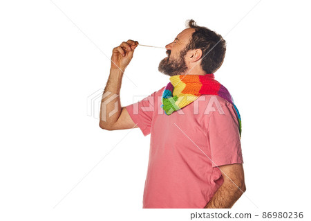 covid prevention on pride day not to spread the virus. man doing a covid test with scarf with lgbt colors. covid prevention on pride day not to spread the virus. man doing a covid test with scarf with lgbt colors. 86980236