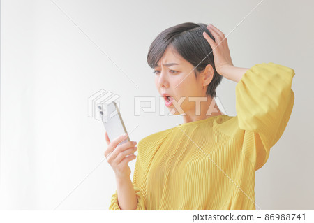 一個女人抱著頭看著她的智能手機 1 86988741