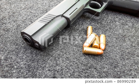 Black artificial hand gun and golden shiny bullets 86990289