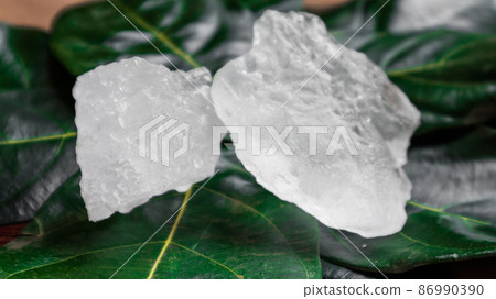 Crystal clear alum cubes or Potassium alum on green leaf. Chemical compound substance. Concept for beauty , spa and underarm treatment industrial.  86990390