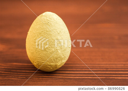 One decorative light yellow egg on a wooden background. 86990826