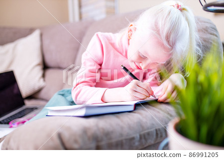 beautiful little girl getting online distance lesson in living room 86991205